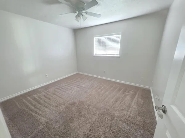 an empty room with windows and fan