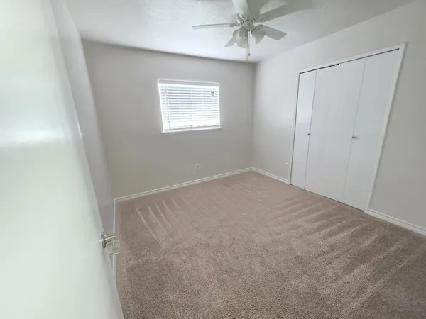 an empty room with windows and fan