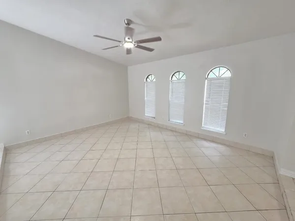 en empty room with chandelier fan and window