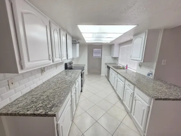 a large white kitchen with granite countertop a sink