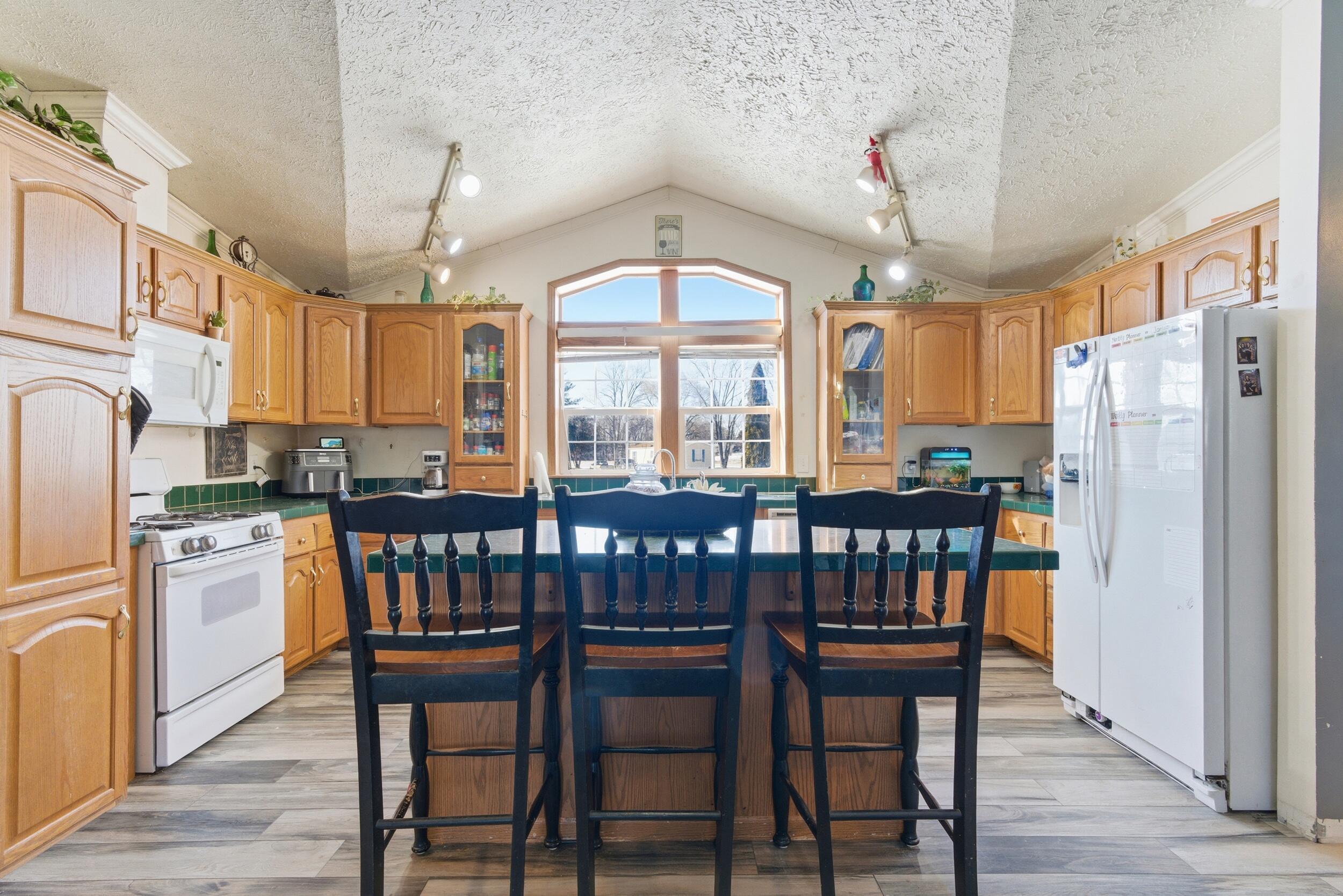 4827 East 994 North Demotte, IN 46310 - Photo 7 of 25 a kitchen with stainless steel appliances granite countertop a dining table chairs refrigerator and cabinets