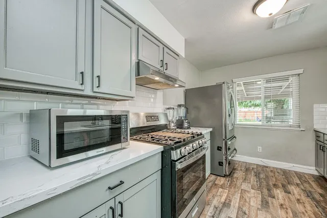 a kitchen with stainless steel appliances granite countertop a stove a sink and a microwave