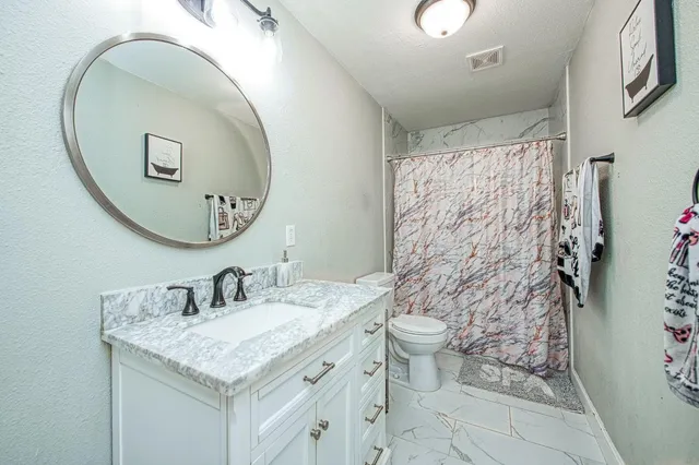 a bathroom with a granite countertop toilet sink and mirror