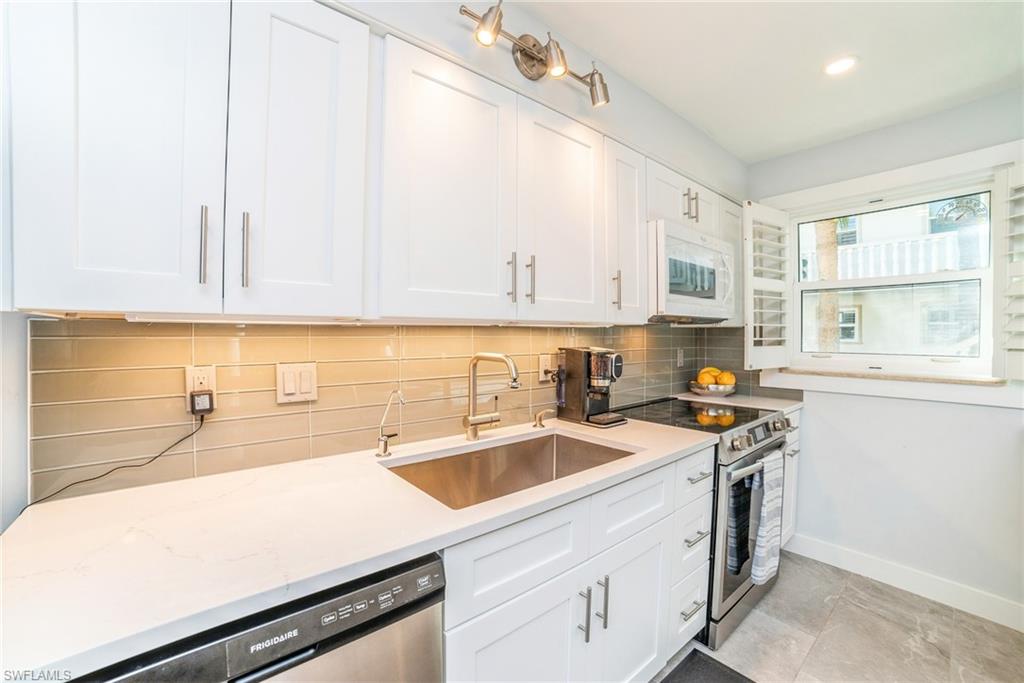 980 7th Avenue South, Unit 101 Naples, FL 34102 - Photo 13 of 32 a kitchen with a sink a stove and cabinets