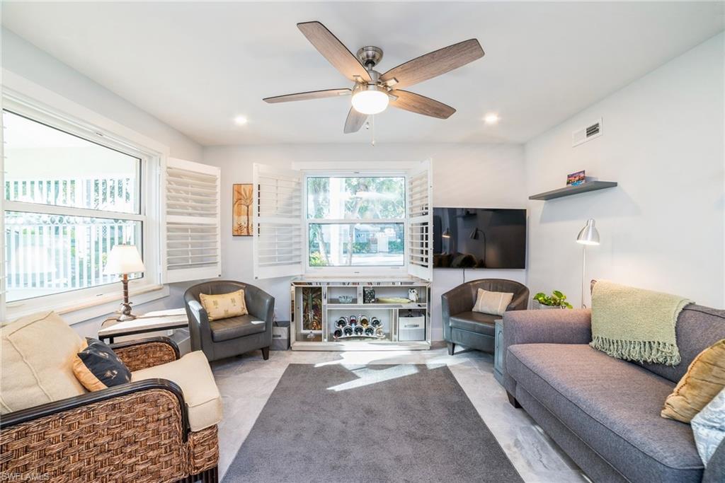 980 7th Avenue South, Unit 101 Naples, FL 34102 - Photo 4 of 32 a living room with furniture a large window and a flat screen tv