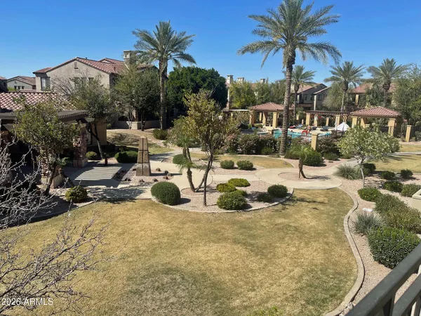 a view of a swimming pool with a lawn chairs under an umbrella with palm trees