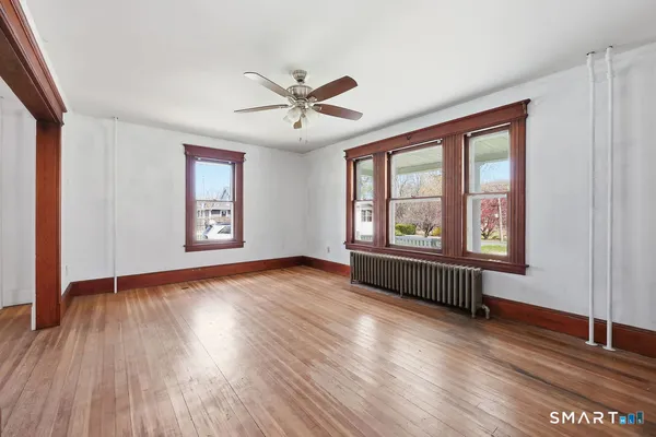 a view of an empty room with wooden floor and a window
