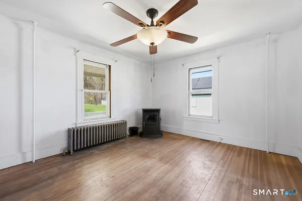 a view of an empty room with wooden floor and a window
