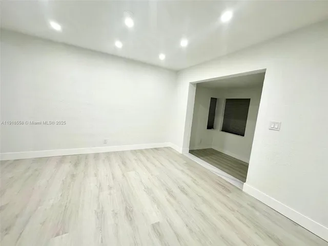 an empty room with wooden floor and mirror