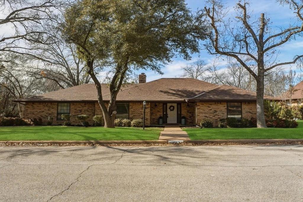 Ranch-style house featuring a front yard, brick siding, a chimney, and a shingled roof