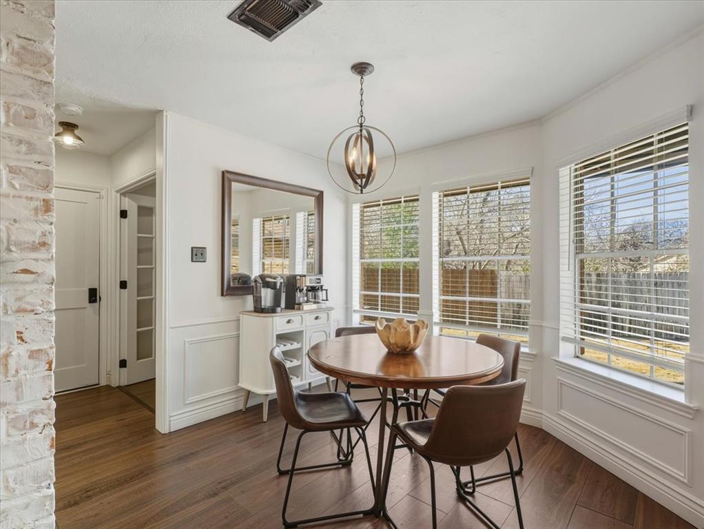 1662 Watson Road Fort Worth, TX 76103 - Photo 12 of 37 Dining room with a wainscoted wall, a decorative wall, dark wood-style floors, and suspended lighting
