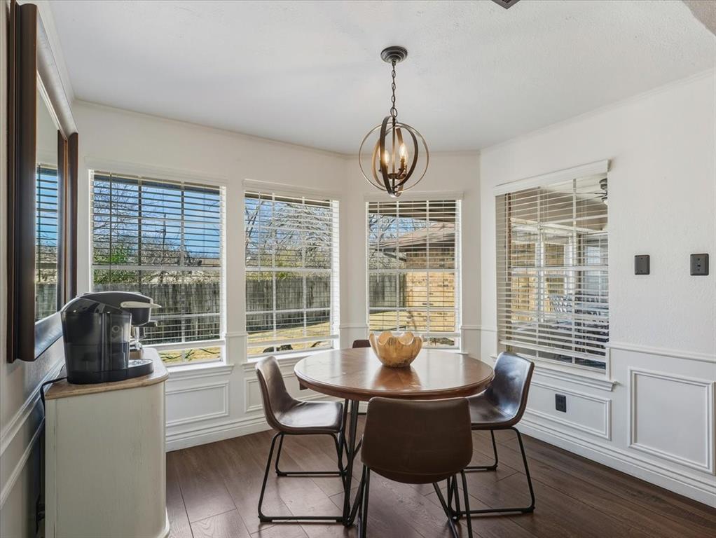 1662 Watson Road Fort Worth, TX 76103 - Photo 13 of 37 Dining room with a decorative wall, wainscoting, dark wood-style floors, hanging lights, and crown molding