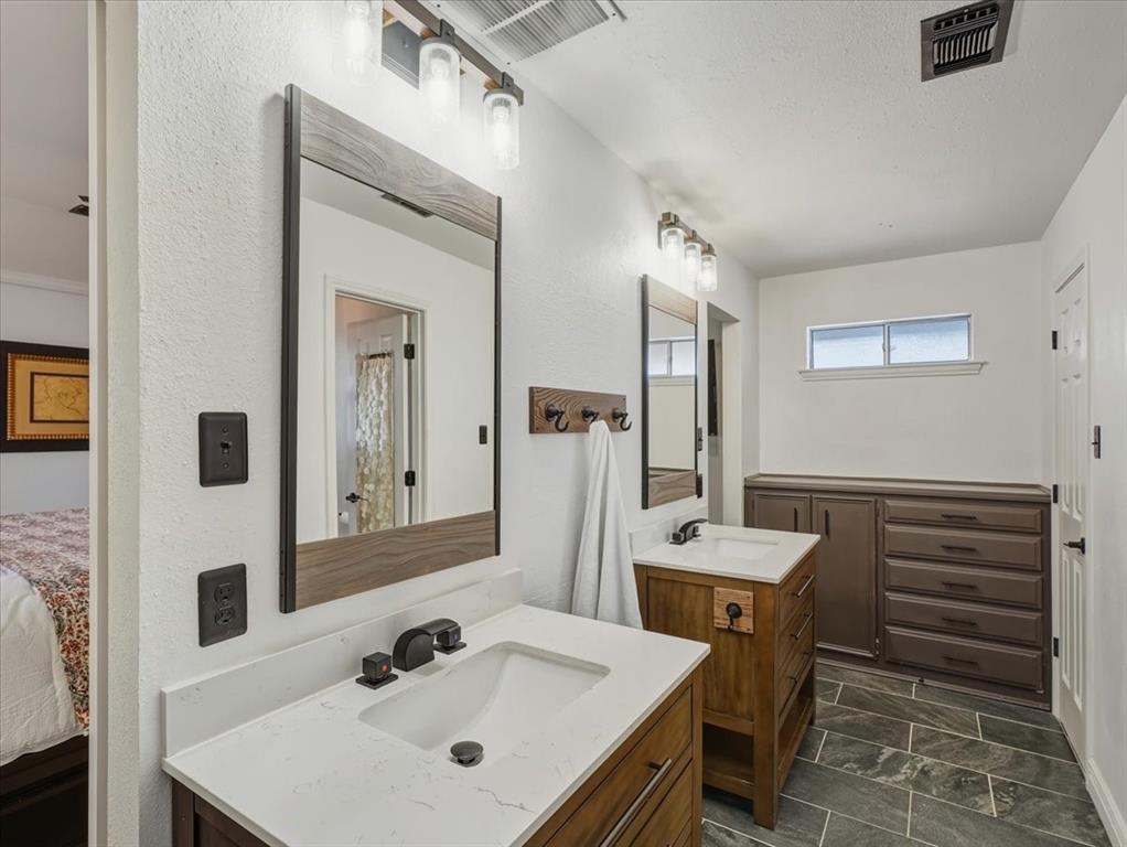 1662 Watson Road Fort Worth, TX 76103 - Photo 18 of 37 Full bath with two vanities, connected bathroom, and dark stone finish floors
