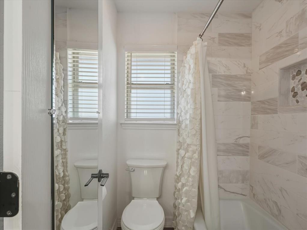 1662 Watson Road Fort Worth, TX 76103 - Photo 20 of 37 Bathroom featuring shower / bath combo with shower curtain and toilet