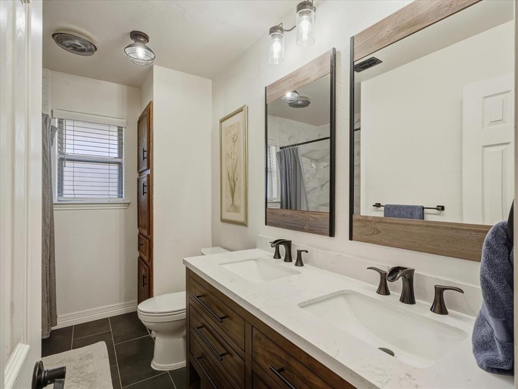 1662 Watson Road Fort Worth, TX 76103 - Photo 24 of 37 Bathroom with a shower with curtain, double vanity, and dark tile patterned flooring