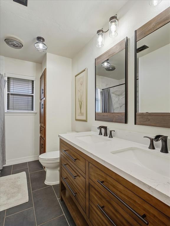 1662 Watson Road Fort Worth, TX 76103 - Photo 25 of 37 Full bathroom with double vanity, a shower with curtain, and dark tile patterned floors