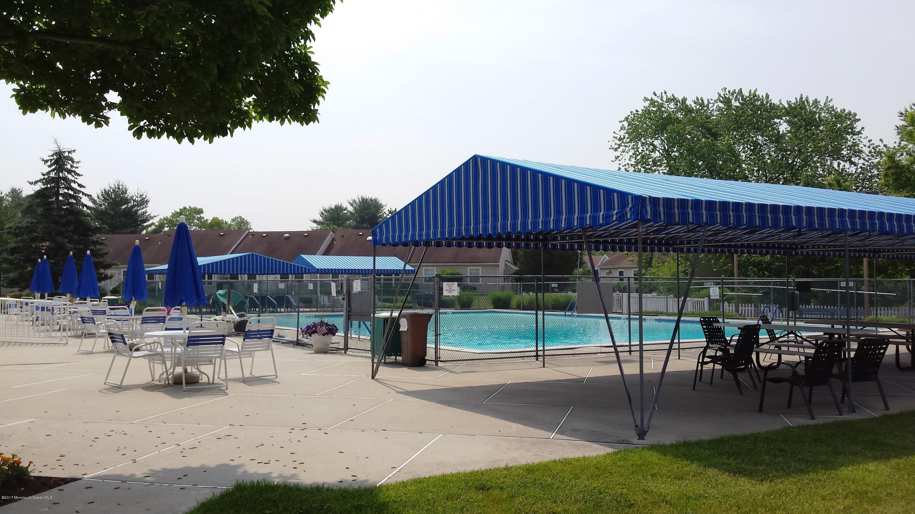 35 A Zacatin Road, Unit 1000 Freehold, NJ 07728 - Photo 16 of 16 a patio with a table and chairs under an umbrella with a small garden
