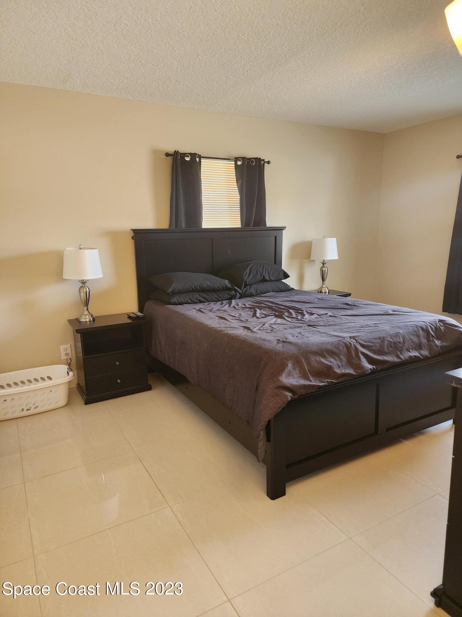 582 North Wickham Road, Unit 89 Melbourne, FL 32934 - Photo 12 of 25 a bedroom with a bed and lamp