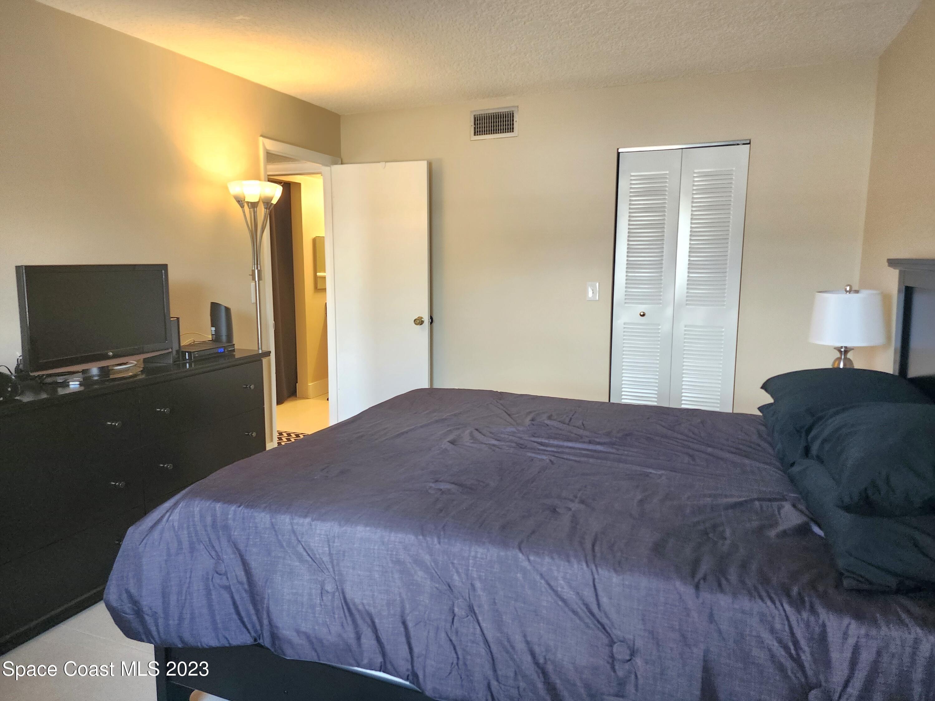 582 North Wickham Road, Unit 89 Melbourne, FL 32934 - Photo 13 of 25 a bedroom with a bed and a flat screen tv