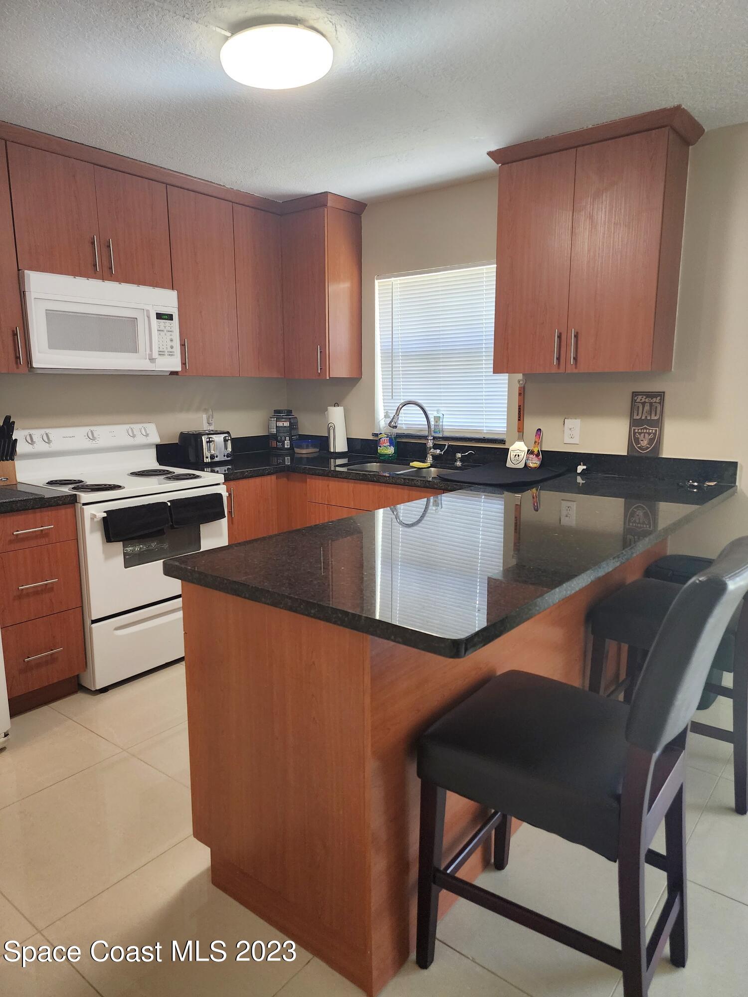 582 North Wickham Road, Unit 89 Melbourne, FL 32934 - Photo 2 of 25 a kitchen with stainless steel appliances granite countertop a sink a stove top oven a counter space and cabinets