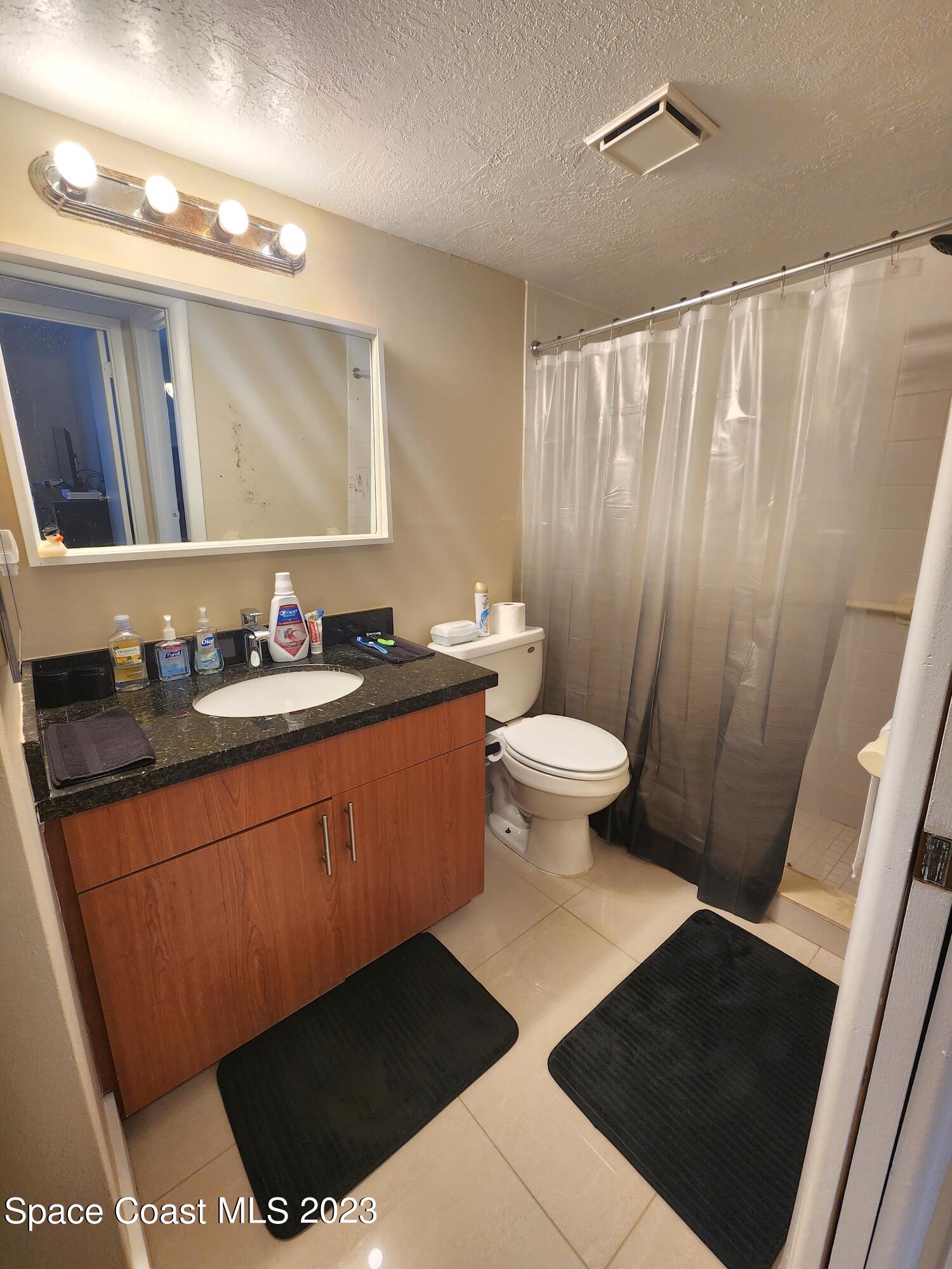 582 North Wickham Road, Unit 89 Melbourne, FL 32934 - Photo 10 of 25 a bathroom with a sink a toilet a mirror a vanity and shower