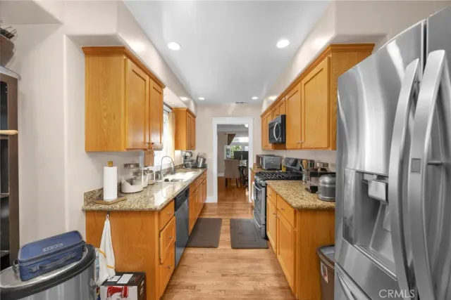 a kitchen with stainless steel appliances granite countertop a refrigerator a sink a stove a washer dryer and white cabinets