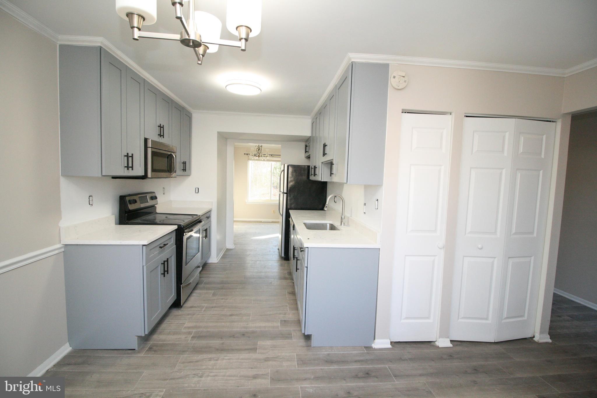 8943 Centerway Road Gaithersburg, MD 20879 - Photo 10 of 34 a kitchen with kitchen island white cabinets and stainless steel appliances