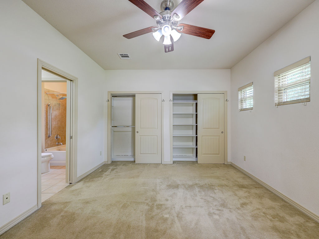 9707 Anderson Mill Road, Unit 22 Austin, TX 78750 - Photo 38 of 39 A well-lit bedroom features plush carpeting and two spacious closets, one with built-in shelving.