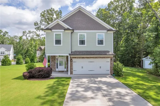 a front view of a house with a garden and trees