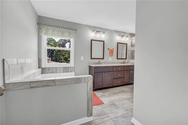 a bathroom with a granite countertop sink mirror and window