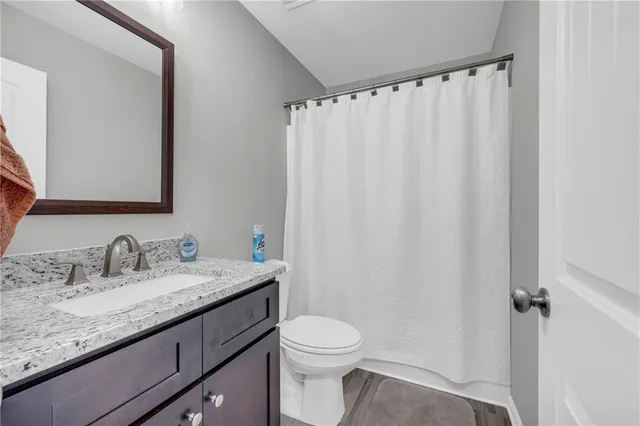 a bathroom with a granite countertop sink toilet and a mirror
