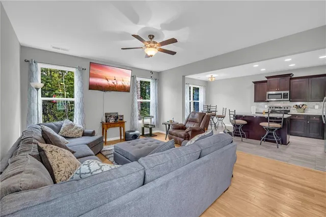 a living room with furniture kitchen view and a large window