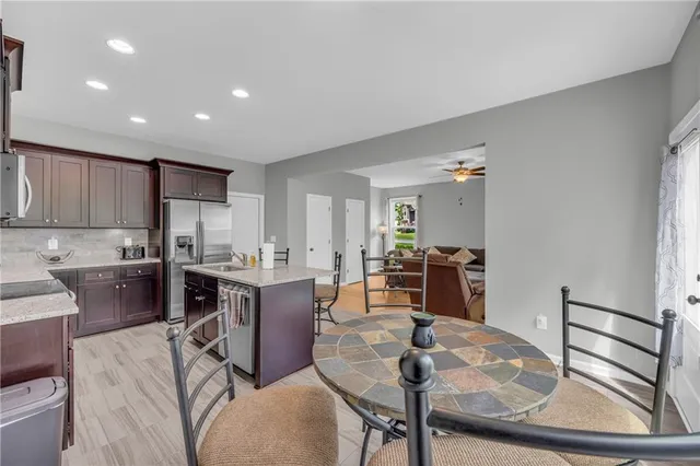 a living room with stainless steel appliances furniture a rug and a kitchen view