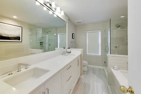 a spacious bathroom with a tub sink and mirror