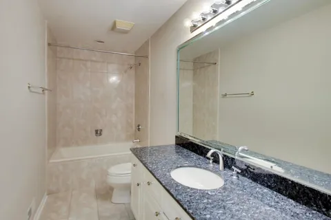 a bathroom with a granite countertop sink a toilet a mirror and shower