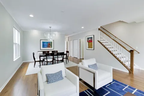 a living room with furniture and a dining table with wooden floor