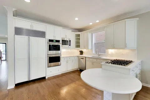 a kitchen with a sink a stove a microwave and white cabinets
