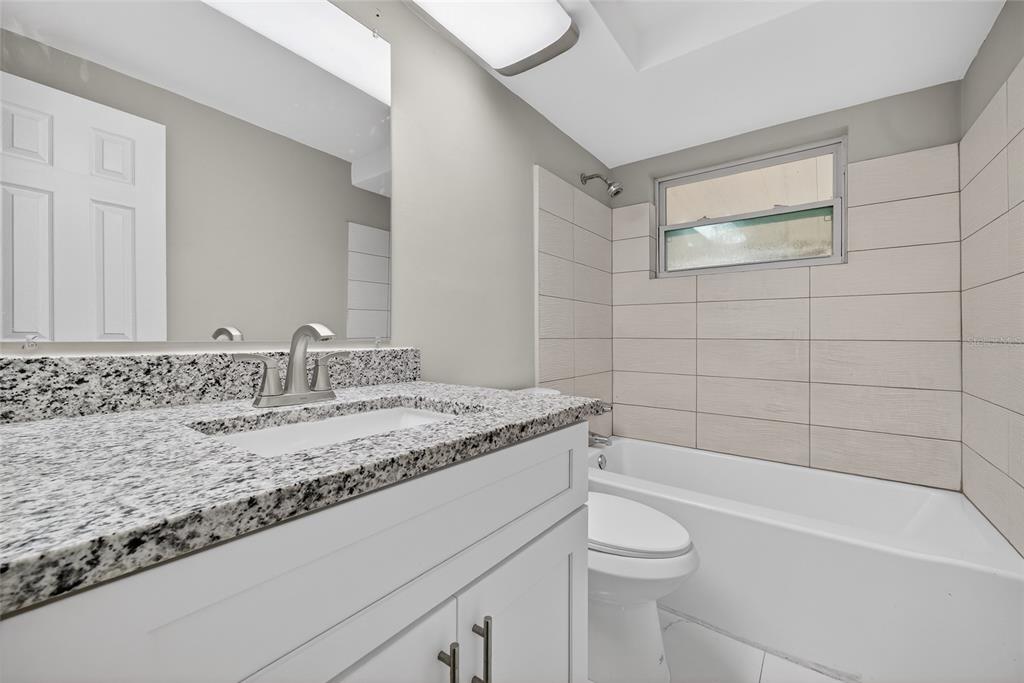1012 Prescott Lane Holiday, FL 34691 - Photo 22 of 45 a bathroom with a granite countertop sink a toilet and bathtub
