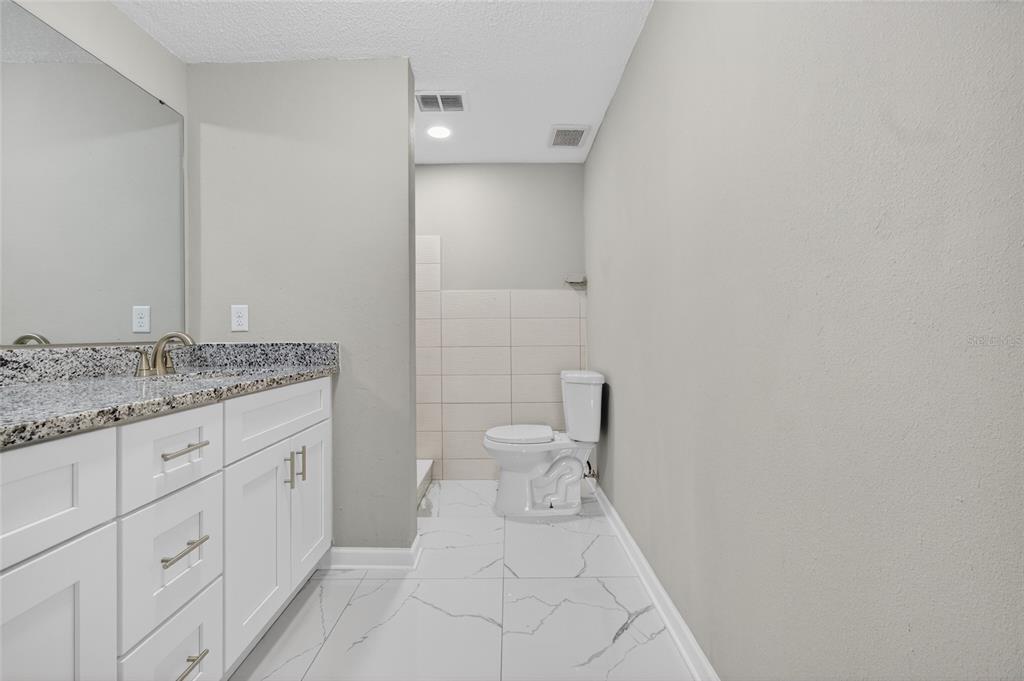 1012 Prescott Lane Holiday, FL 34691 - Photo 29 of 45 a spacious bathroom with a granite countertop sink a toilet and a mirror