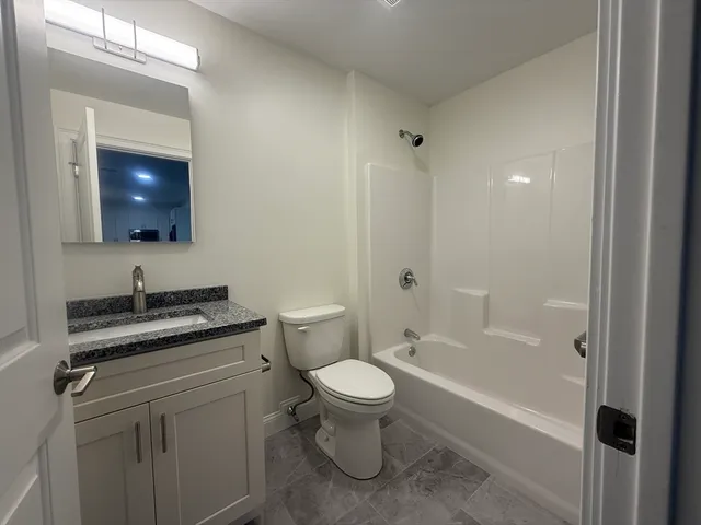 a bathroom with a granite countertop toilet a sink and a bathtub