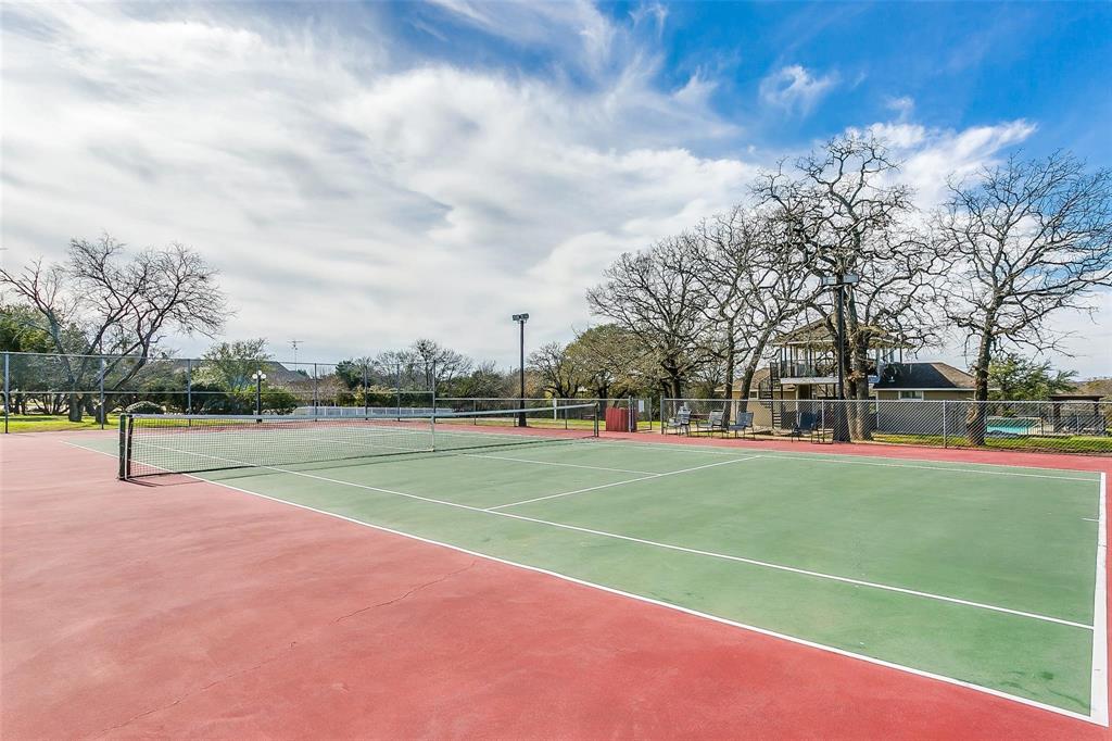 38098 Misty Ridge Drive Whitney, TX 76692 - Photo 19 of 25 Tennis court featuring a red and green playing surface, perimeter fencing, and mature trees