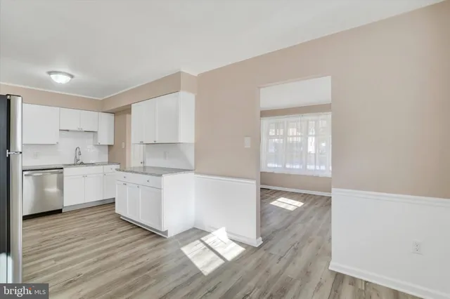 a large white kitchen with wooden floors and white stainless steel appliances