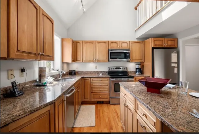 a kitchen with stainless steel appliances granite countertop a sink stove microwave and refrigerator