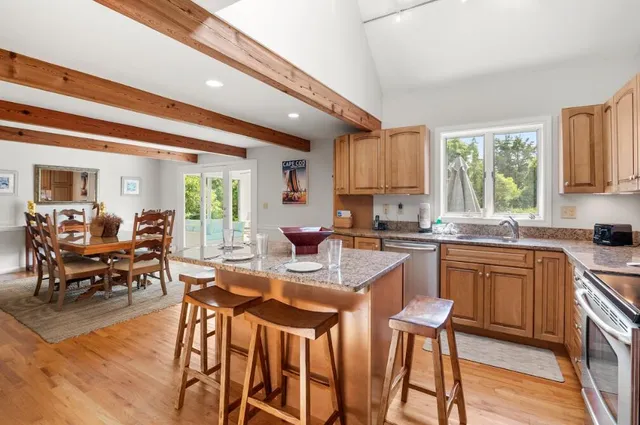 a kitchen with stainless steel appliances granite countertop dining table chairs cabinets and a window