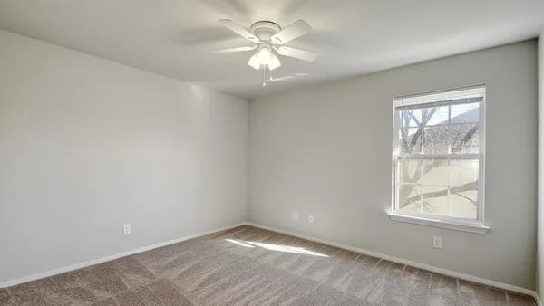 an empty room with windows and chandelier fan