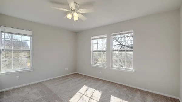an empty room with a window and a ceiling fan