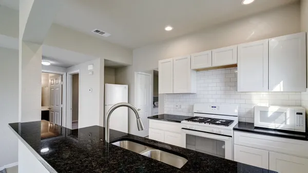 a kitchen with stainless steel appliances granite countertop a stove a sink and a white cabinets