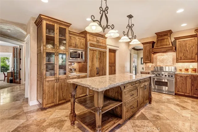 a kitchen with stainless steel appliances granite countertop a stove top oven a sink a dining table and chairs with wooden floor