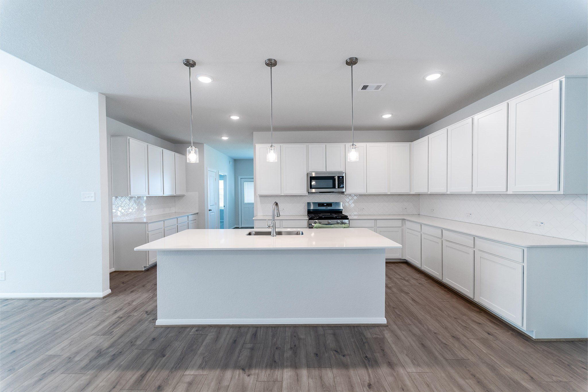 418 Hazy Meadows Drive Beasley, TX 77417 - Photo 9 of 17 a large kitchen with stainless steel appliances a large kitchen island hardwood floor sink stove and wooden cabinets