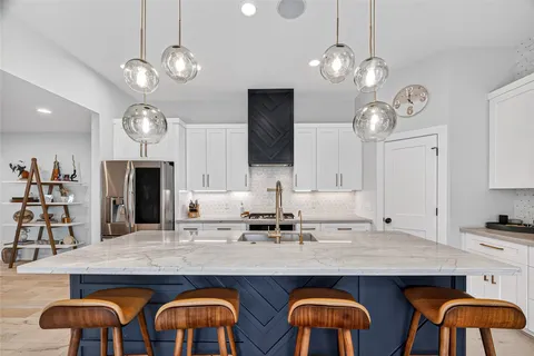 a kitchen with kitchen island granite countertop a sink cabinets and stainless steel appliances